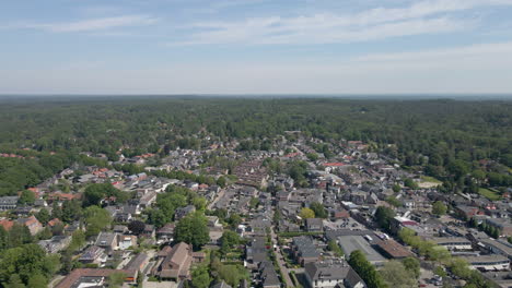 Beautiful-aerial-of-small-town-surrounded-by-a-green-forest-in-summer