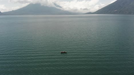 Man-rowing-on-boat-on-Atitlan-lake-with-volcano-San-Pedro-in-background,-Guatemala