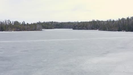 Aerial-Dolly-Vorwärts-über-Schmelzenden-Zugefrorenen-See-Mit-Noch-Sichtbaren-Eisstraßen-In-Kanada
