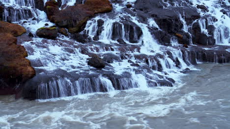 Waterfall-Cascading-Down-To-Hvita-River-Through-Mossy-Rocks