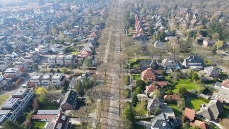 Aerial-of-oncoming-car-driving-on-a-long-road-in-a-beautiful-small-town