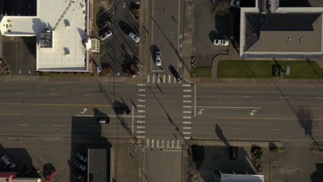 Cars-Drive-Through-Four-Way-Intersection-With-Traffic-Stop-Lights-In-Urban-Landscape-During-Sunny-Day