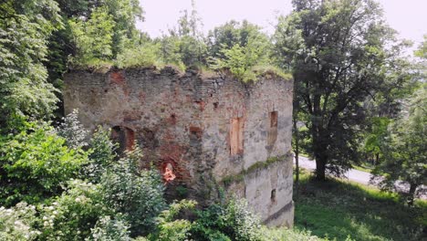 Remnants-of-ancient-defensive-tower-in-overgrown-park,-aerial-view