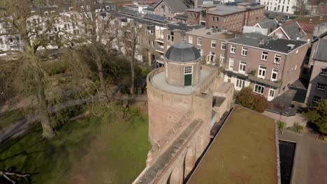 Slow-forwards-aerial-approaching-top-of-the-historic-Bourgonje-stronghold-tower-and-city-wall-with-park-landscape-in-Zutphen,-The-Netherlands