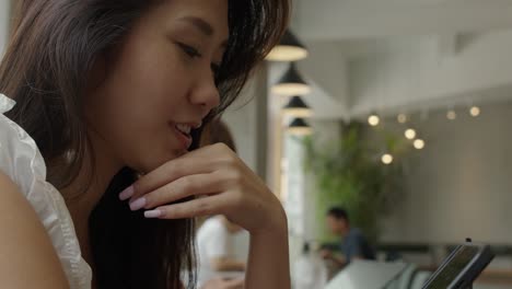 Beautiful-young-charming-Asian-girl-having-internet-call-on-her-tablet-in-coffee-shop