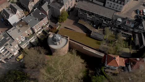 Top-down-reveal-and-fly-over-historic-Bourgonje-stronghold-tower-and-city-wall-among-the-new-and-old-parts-of-the-Dutch-medieval-Hanseatic-cityscape-of-Zutphen