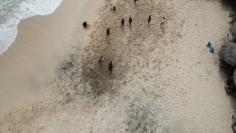 aerial-view,-showing-tourists-playing-beach-soccer-on-Watu-Lawang-beach,-Gunung-Kidul,-Yogyakarta,-Indonesia