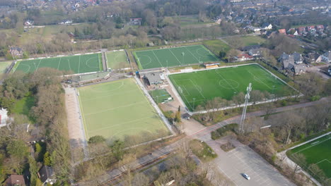Wide-jib-up-of-green-soccer-fields-at-the-edge-of-small-town
