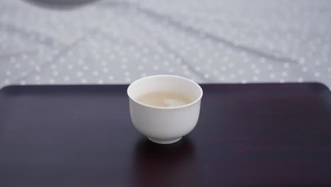 Teekanne-Aus-Porzellan-Gießt-Tee-Eine-Schöne-Weiße-Teetasse-Auf-Einem-Holztablett