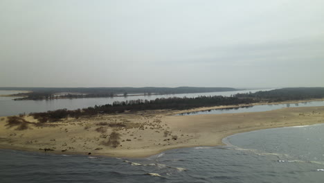 Aerial-wide-shot-of-waves-of-Baltic-Sea-sandy-island-and-River-Mouth-of-Vistula-River-in-background