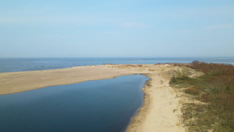 Aerial-side-shot-of-Vistula-River-ended-in-sand-bank-of-Mewia-Lacha-Nature-Reserve-during-sunny-day-and-blue-Baltic-Sea-in-background