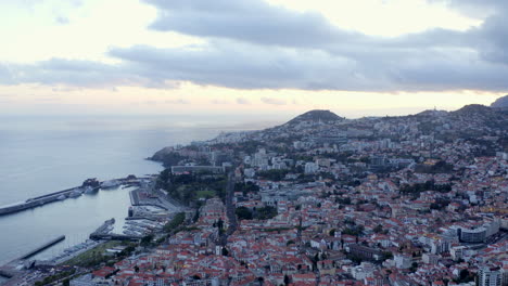 Drone-aerial-footage-flying-over-Funchal-city-in-Madeira-island,-Portugal-with-views-out-to-Atlantic-ocean