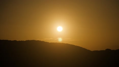 Slow-motion-shot-of-setting-sun-shining-golden-light-over-hill-in-Sardinia,-Italy