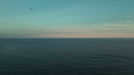 Aerial-view-of-deep-blue-sea-with-small-plane-passing-by