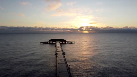 Shimmering-golden-hour-sunrise-ocean-Deal-pier-Kent-landmark-aerial-dolly-right