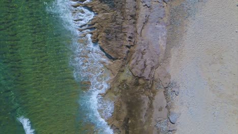 Slomotion-aerial-drone-clip-moving-over-a-sandy-beach-and-a-rock-formation-in-Kavala,-Macedonia,-Greece