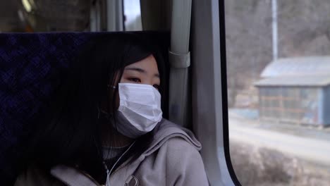 Melancholic-girl-wearing-facemask-looking-out-from-train-window-slow-motion