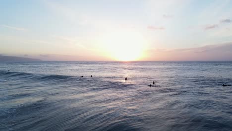 Surfers-at-sunset-on-the-waters-of-North-Shore-in-Oahu,-Hawaii,-wide-shot