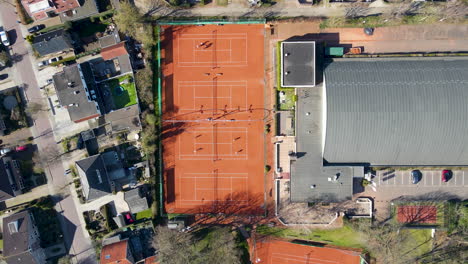 Top-down-aerial-of-busy-tennis-court---drone-setting-down