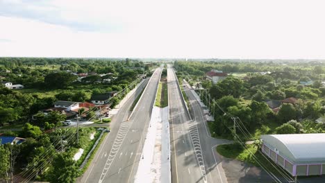 Wild-short-of-aerial-view-railway-crossing-bridge-and-tree-forest-countryside-with-traffic-on-the-road-in-Khonkaen,-Thailand