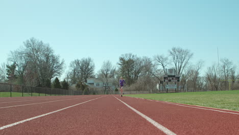 Teen-girl-athlete-running-track-towards-and-past-camera-in-slow-motion-on-a-pretty-day