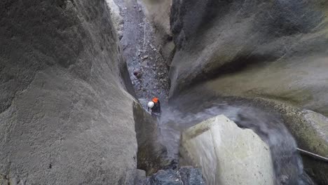 Frau-Canyoneer-Abseilen-Wasserfall-In-Kalksteinschlucht-Weit-Unten