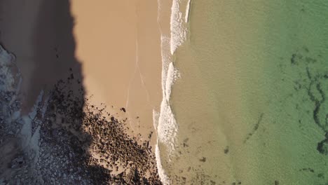 Top-down-aerial,-waves-washing-on-sand-beach-in-Burgau,-Algarve