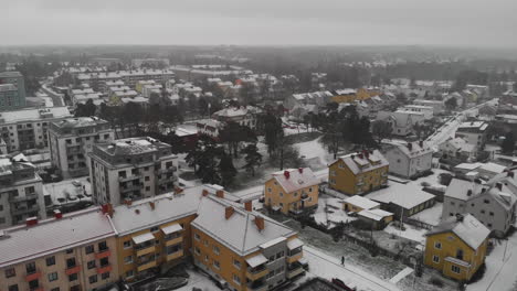 Aerial-pull-out-landscape-view-of-a-small-rural-town-with-houses-and-homes-covered-with-snow,-winter-season-in-Trollhättan,-Sweden