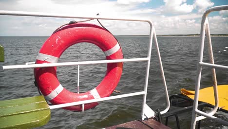 shot-of-the-red-lifebuoy-on-the-fence-of-the-boat,-wavy-sea