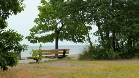 An-empty-park-bench-beside-a-bike-trail,-overlooking-Lake-Ontario