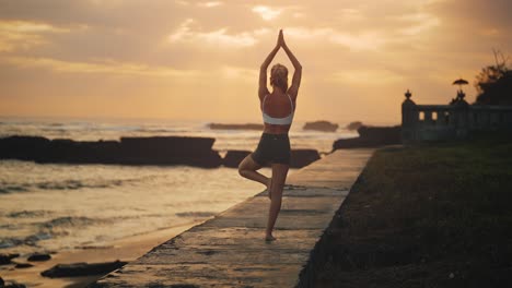 Fit-woman-on-Bali-shore-during-magical-sunset-doing-tree-pose,-balance