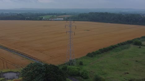 Electricity-steel-pylon-high-voltage-wires-in-countryside-agricultural-farm-field-aerial-view-early-morning-wide-tilt-down-push-in
