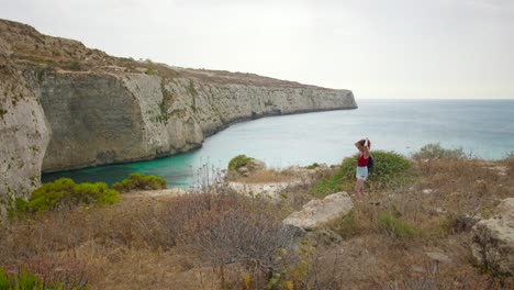 Weibliche-Wanderer,-Die-Haare-Binden,-Während-Sie-An-Der-Küste-Von-Fomm-Ir-rih-Bay-Auf-Der-Insel-Malta-Stehen