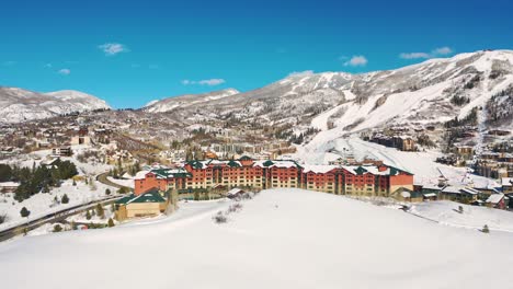 Aerial-View-Of-Ski-Lodge-Near-Ski-Resort-With-Snowy-Mountain-In-Background-In-Steamboat-Springs,-Colorado
