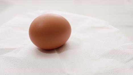 Cierre-La-Rotación-De-Huevos-Orgánicos-Sobre-Un-Fondo-De-Papel-Blando-Blanco