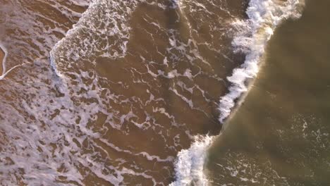 Spinning-slow-motion-birds-eye-view-of-waves-breaking-in-the-sandy-shore-in-a-Caribbean-Sea-beach