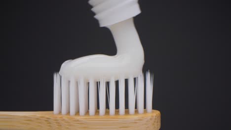Super-close-up-camera-shot-of-toothpaste-dropping-on-the-toothbrush