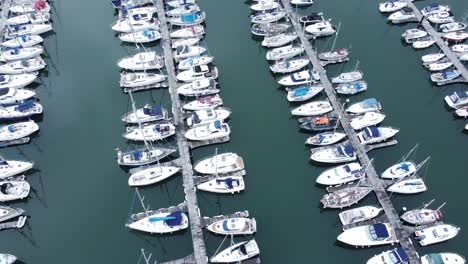 Top-down-aerial-view-above-luxury-yachts-parked-on-turquoise-ocean-water-marina