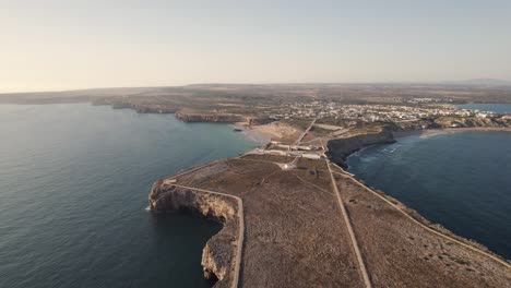 Fliegen-Sie-über-Eine-Schmale-Landzunge-In-Richtung-Der-Festung-Sagres,-Algarve,-Portugal