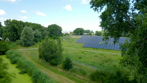 Luftflug-über-Schöne-Grüne-Sonnenkollektorfarm-Erneuerbare-Energie-Zwischen-Bäumen