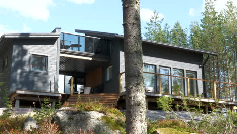 Beautiful-looking-modern-Finnish-cabin-home-near-pine-tree-forest,-pan-right-view