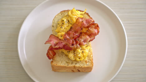 bread-toast-with-scramble-egg-and-bacon-on-white-plate