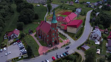 Huge-brick-church-with-red-roof-and-group-of-people-standing-in-front-of-it