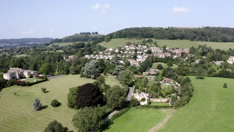 AERIAL---Stouts-Hill,-houses-and-hills-in-Uley,-Cotswolds,-England,-pan-left