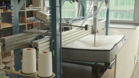 Mattress-being-tested-with-hydraulic-press-in-mattress-production-facility---wide
