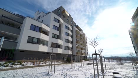 modern-suburb-with-block-of-flats-and-snowy-park-on-a-sunny-day,-dolly-in