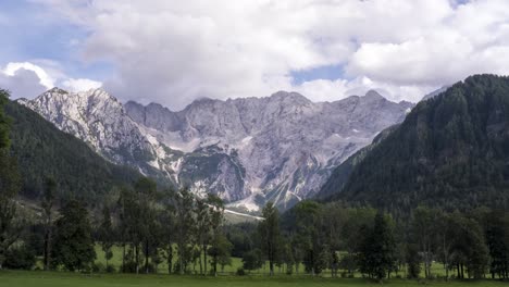 Timelapse-of-clouds-above-mountains-and-meadows-with-trees-in-front,-pristine-rural-landscape-of-European-Alps,-Jezersko,-Slovenia