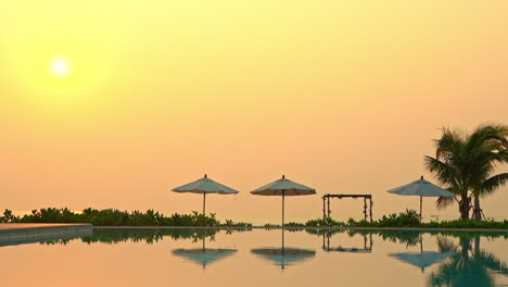 A-brilliant-pink,-yellow-and-golden-sunset-reflects-in-an-exclusive-resort-summing-pool