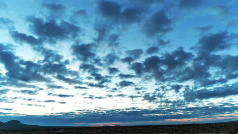 Nubes-En-Movimiento-Rápido-Cruzan-El-Cielo-Sobre-El-Paisaje-Del-Desierto-De-Mojave-Mientras-Sale-El-Sol---Lapso-De-Tiempo