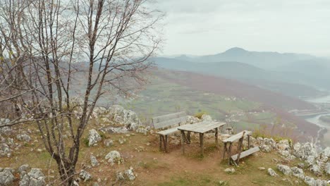 Old-wooden-bench-overlooking-mountain-valley,-scenic-landscape-aerial-view